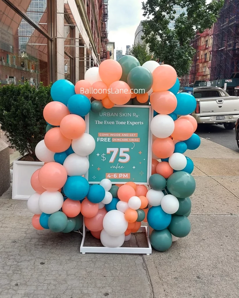 Corporate event backdrop with orange, blue, green, and white balloons at the entrance of a corporate center by Balloons Lane in Brooklyn.