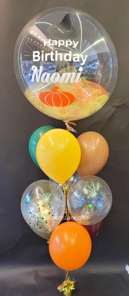 Balloon bouquet featuring confetti, peach, yellow and orange balloons, along with customized birthday balloons, in Brooklyn.