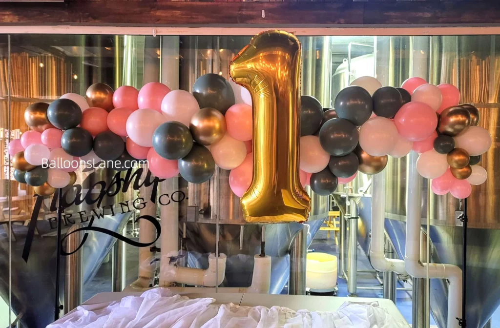 Balloon backdrop with large number 1 balloon along with pink, gold, and black balloons in Staten Island to celebrate 1st birthday