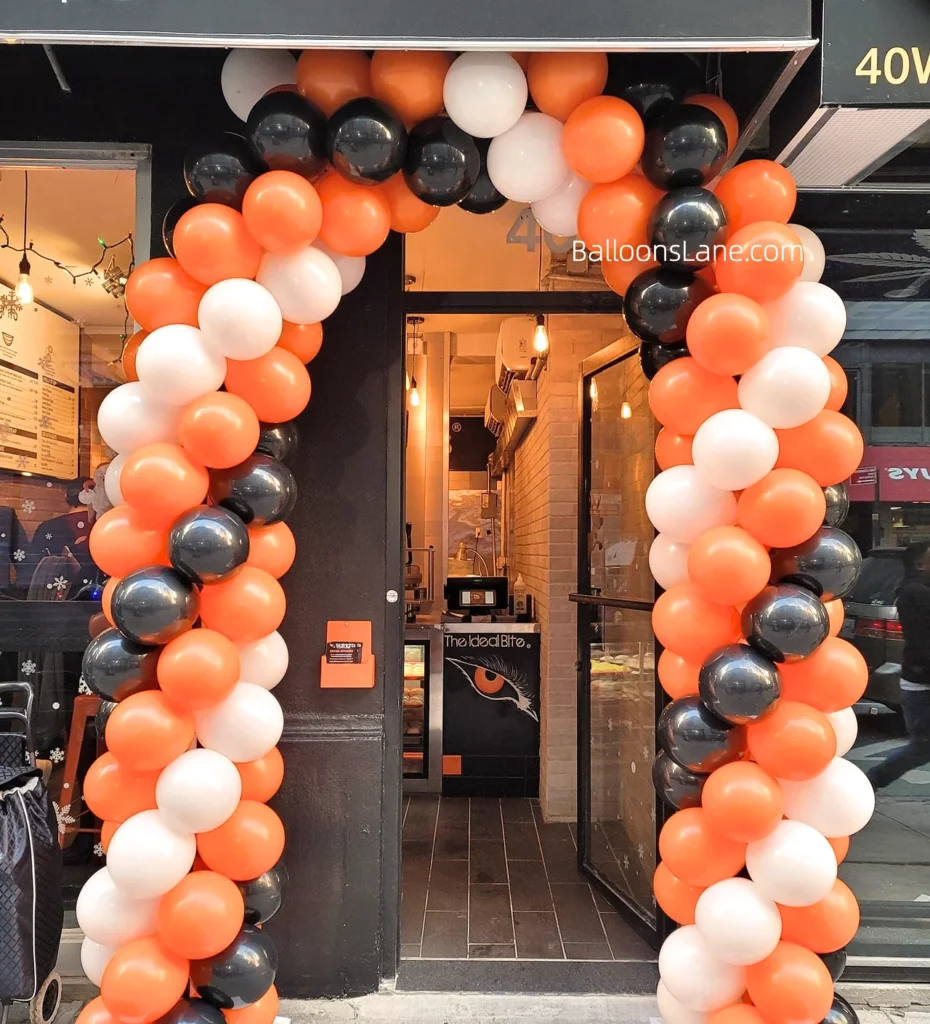 Halloween-themed balloon arch featuring orange, red, and white balloons in NYC.