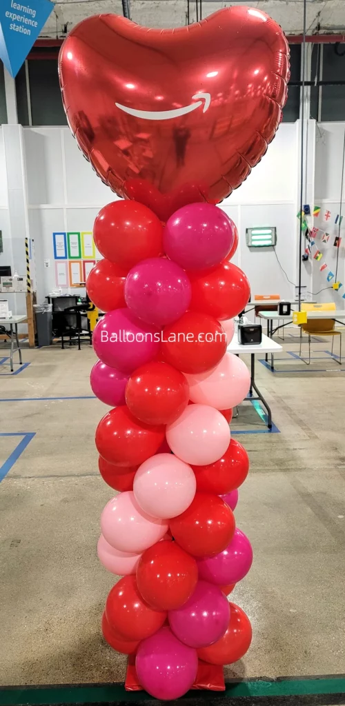 Large red heart balloon with pink and red balloon column.
