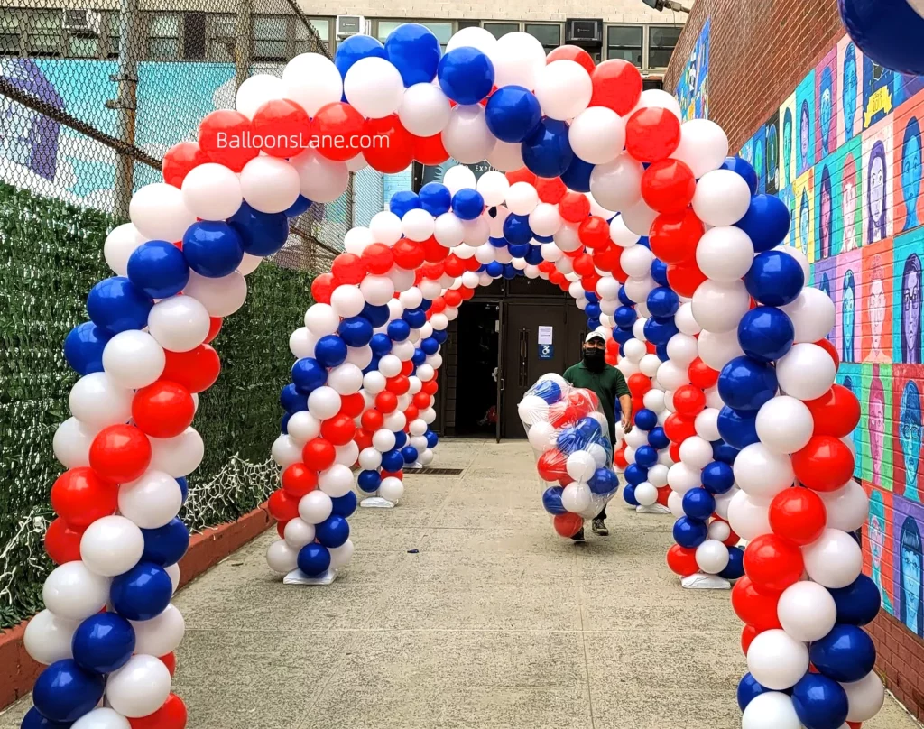Arch made of red, white, and blue latex balloons at the entrance of the school.