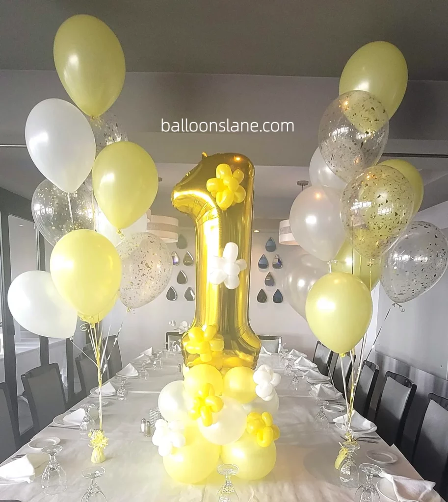 Beautiful balloon bouquet in lime yellow, white, and confetti balloons, along with a gold Number 1 balloon stand, to celebrate 1st birthday in Brooklyn