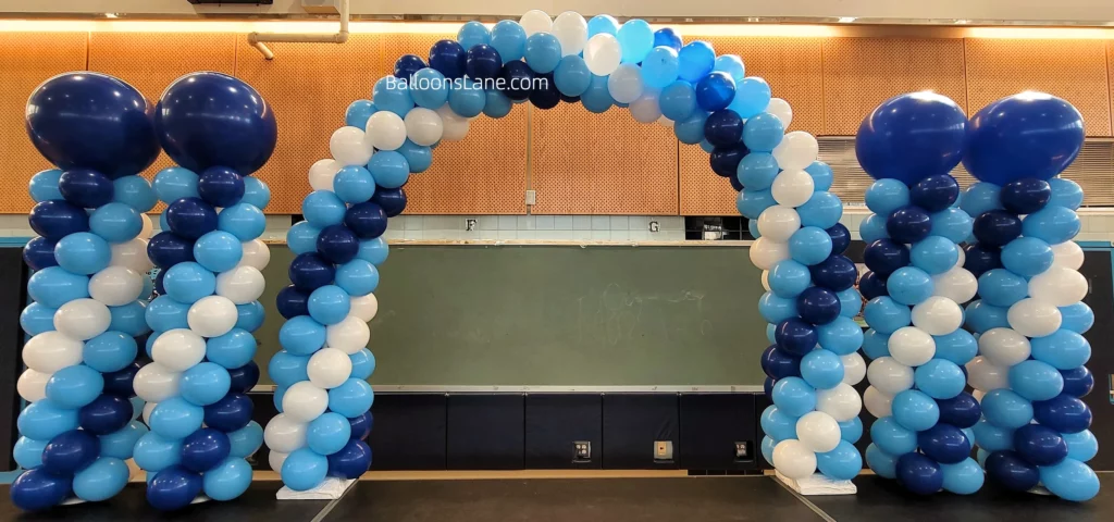 : Balloon arch and column in dark blue, light blue, and white, topped with a large blue balloon.