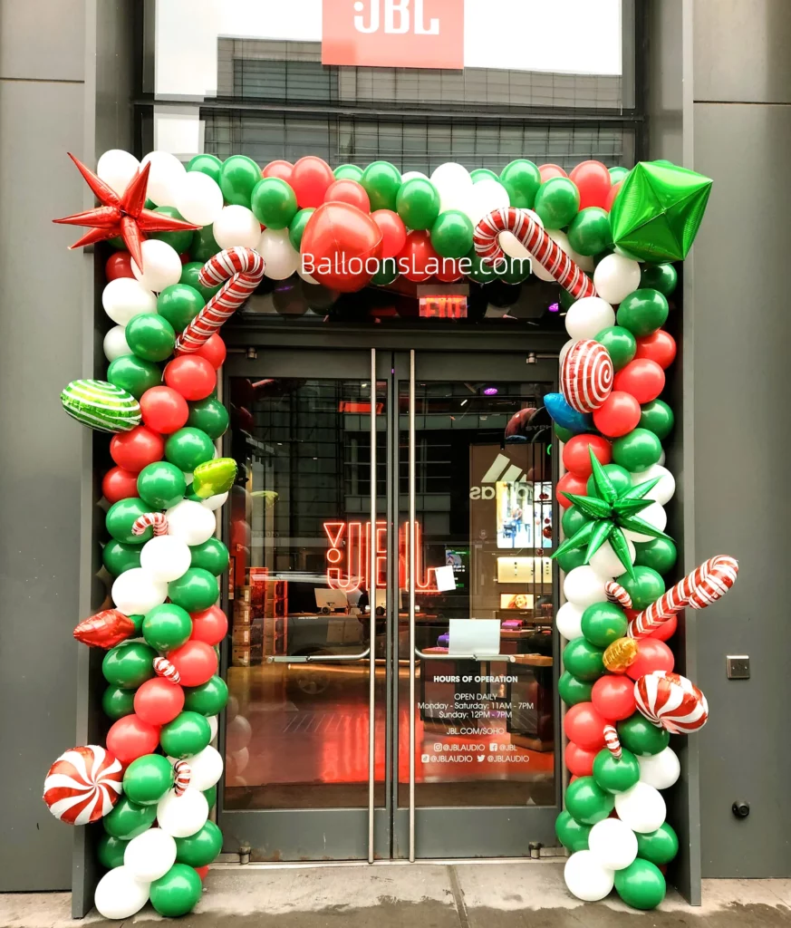 Corporate event celebration with green, red, and white balloons arch, adorned with red and white star balloons and theme balloons, during Christmas days.