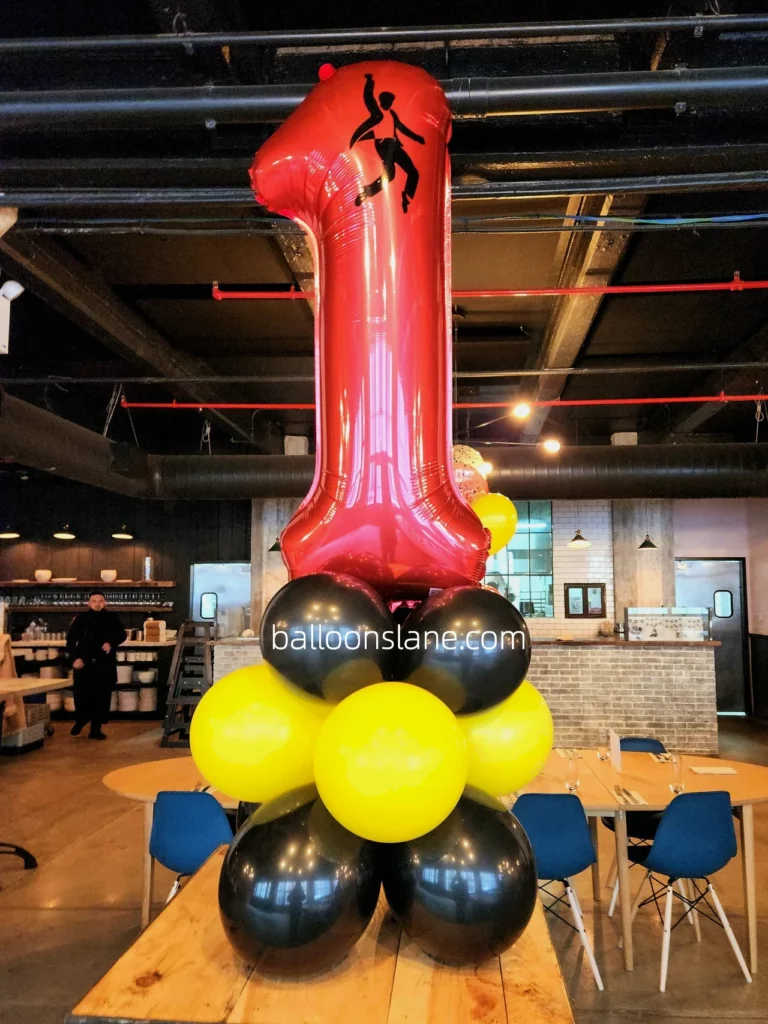 A beautiful balloon bouquet in yellow, black colors, featuring a red number of "1" balloons, was created by Balloons Lane in Brooklyn for a first birthday balloon decoration.