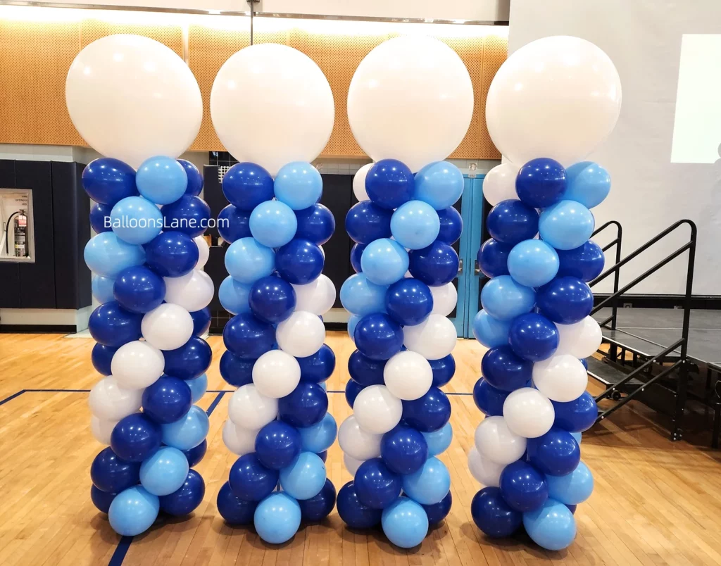 Column made of dark blue, light blue, and white balloons with a large balloon on top.