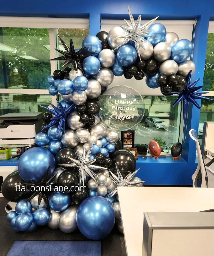 Half arch of Onyx Black, Chrome® Blue, and Chrome® Silver balloons in multiple sizes, with foil star balloons and a clear personalized birthday balloons, in New Jersey.