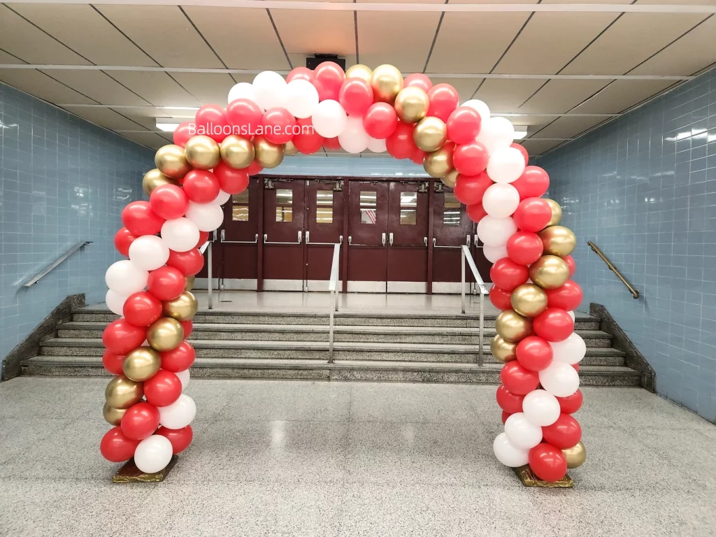 Arch made of red, white, and gold latex balloons.