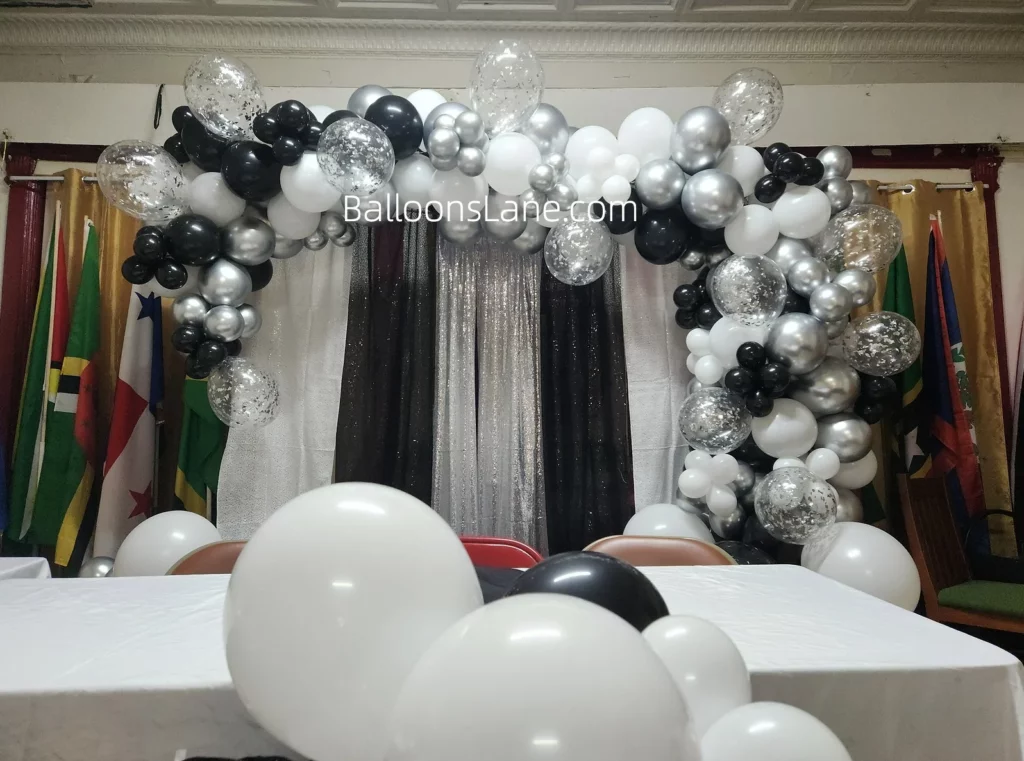 Half arch of black, white, and silver balloons in multiple sizes, along with silver confetti balloons, to celebrate a themed birthday or graduation in Staten Island.