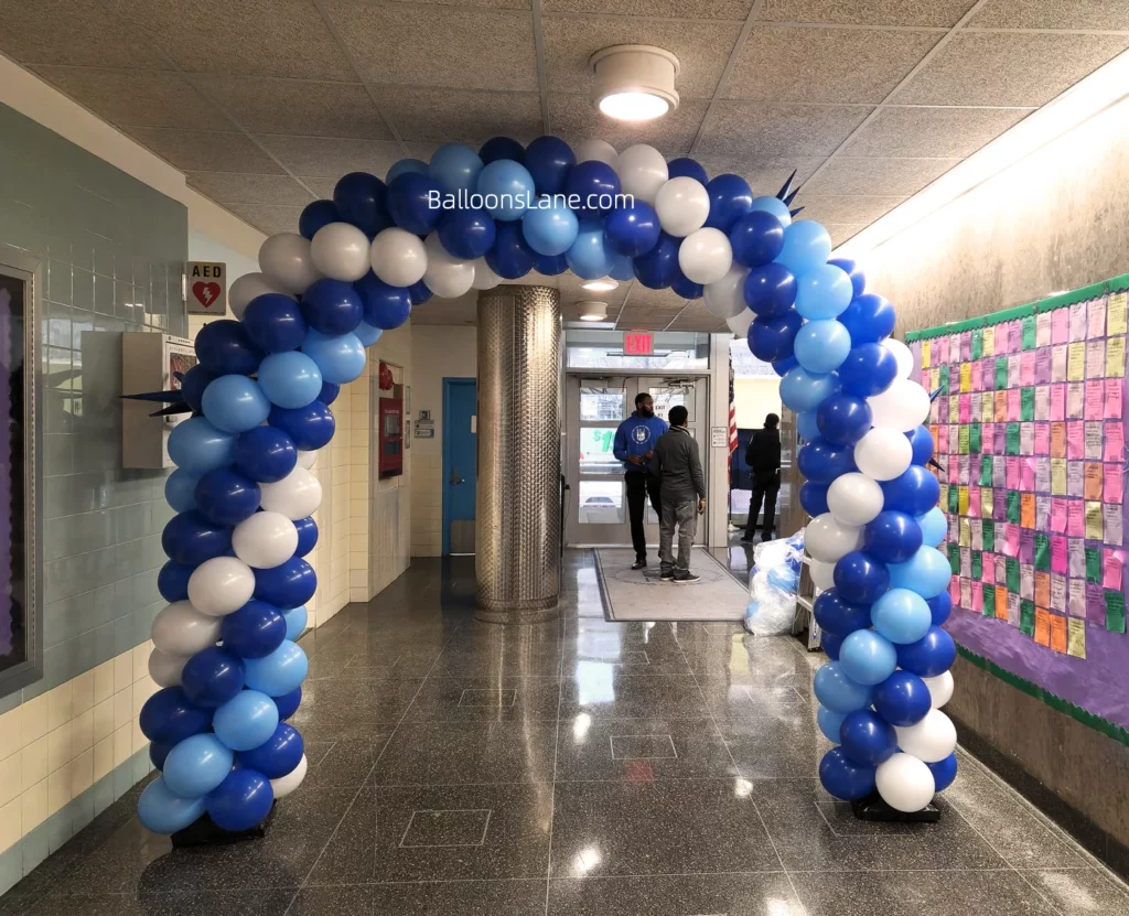 A balloon garland in navy blue, royal blue, and white displayed in front of a school.