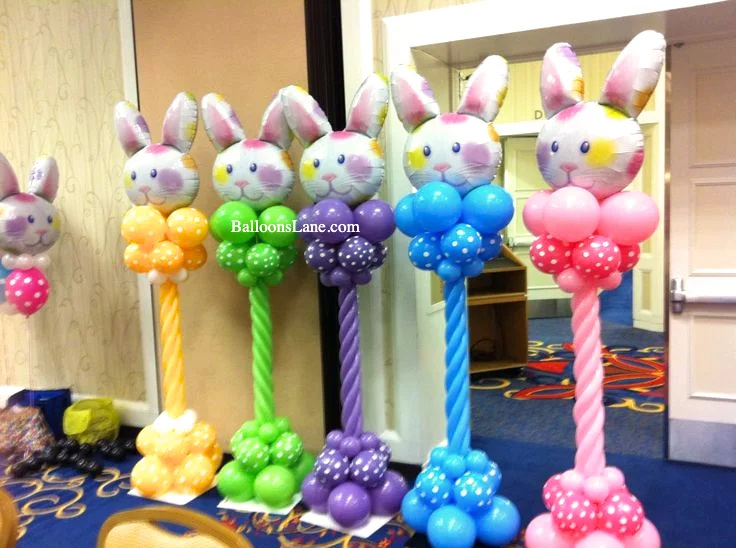 A bunny balloon column in purple, green, blue, and pink, accompanied by customized bunny face dotted balloons and twisted balloons, set in New York City.