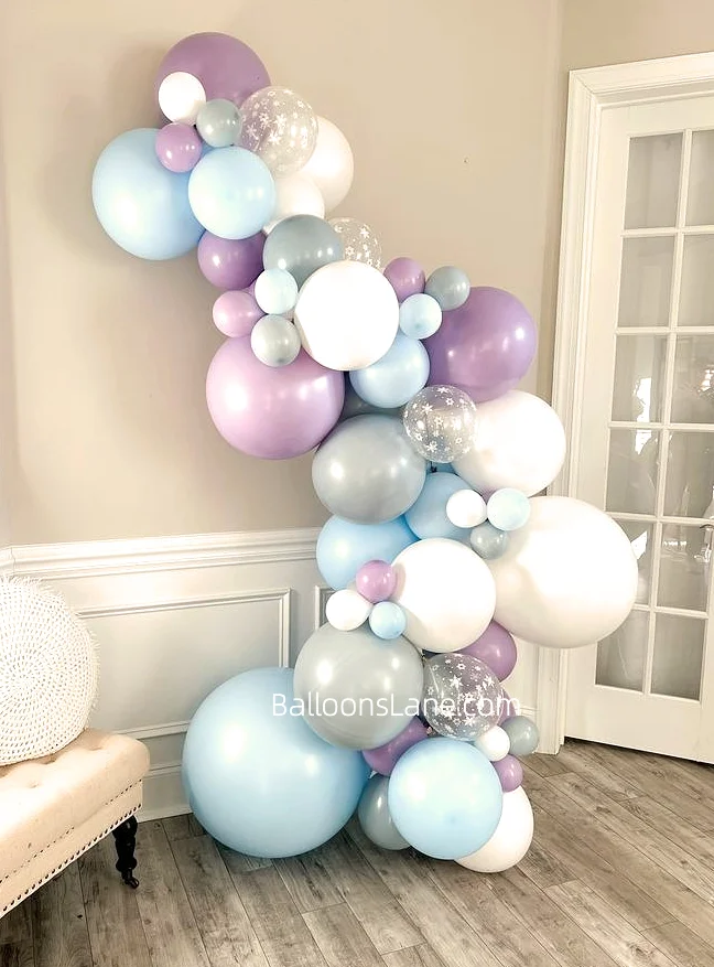 A balloon garland featuring lavender, white, light blue, and clear balloons, perfect for celebrating winter parties.