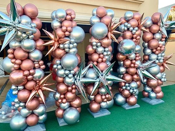 Eye-catching Chrome® Rose Gold and Chrome Light Blue latex balloons, accented with Mylar star balloons, arranged in a stylish column for a vibrant event.