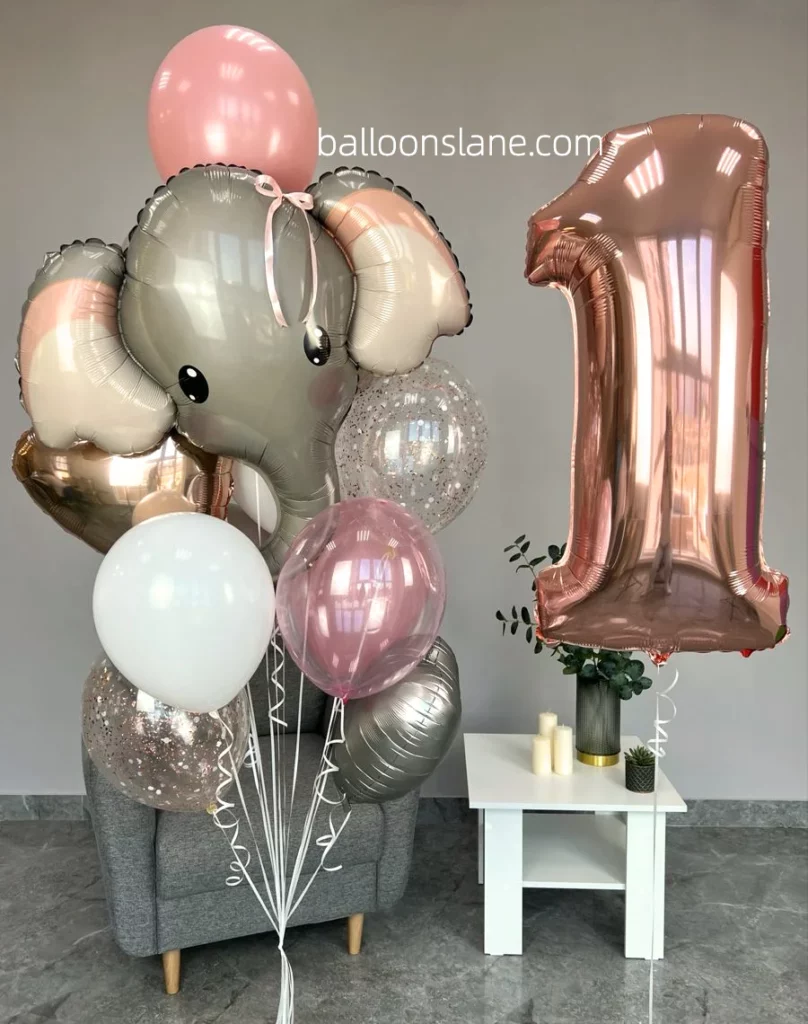Beautiful textured pink balloon, heart-shaped balloon, pink shade balloon, and glittery number "1" balloon along with elephant theme on top of pink silver chrome balloon in NJ