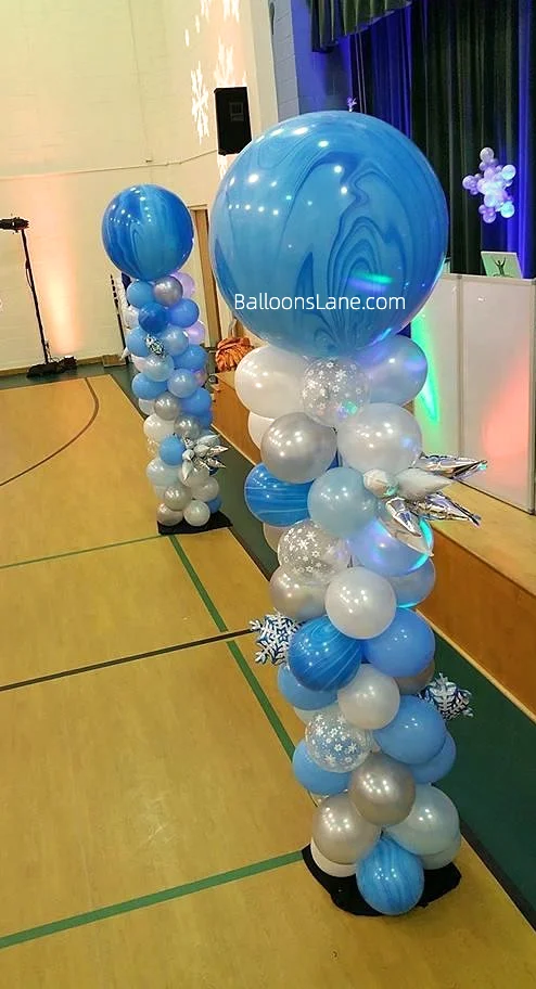 A Winter Wonderland balloon column featuring chrome blue, white, and silver balloons, ideal for a Snow Queen Princess-themed girl's birthday party or baby shower.