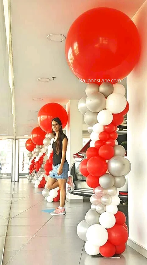 Striking big red latex balloon column adorned with red, white, and silver balloons, designed to celebrate Valentine's Day and placed at the entrance of your showroom.
