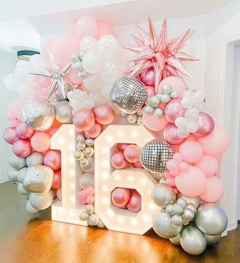 Sweet 16 birthday celebration with pink latex balloons, silver latex balloons, white balloons, and a silver and pink star foil balloon backdrop in NYC.