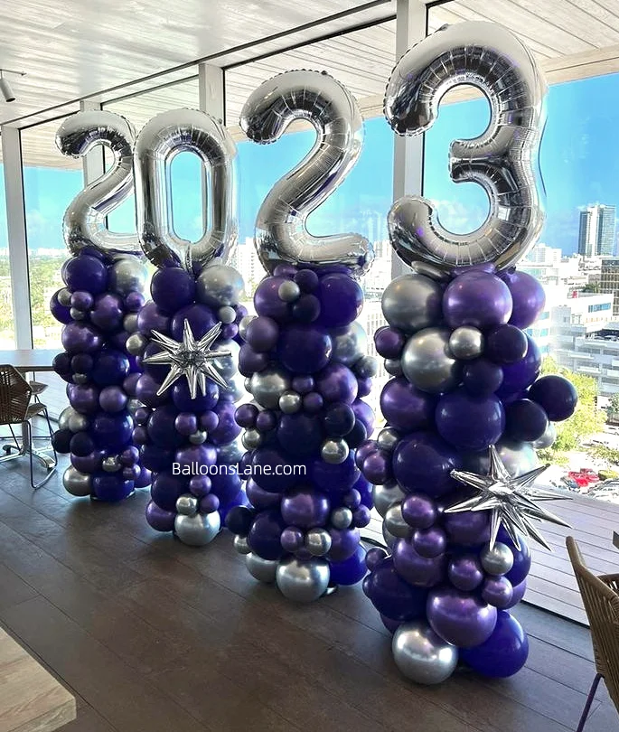 Striking silver number balloon column surrounded by blue, purple, and silver latex balloons, creating a vibrant and celebratory display.