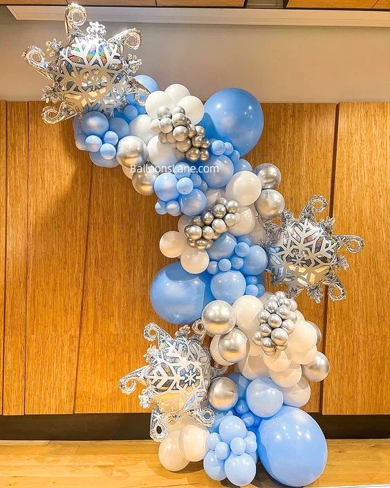 A Winter Wonderland balloon garland arch kit featuring 160 pieces of large snowflake chrome blue, white, and silver balloons, perfect for a Snow Queen Princess themed girl's birthday party or baby shower.