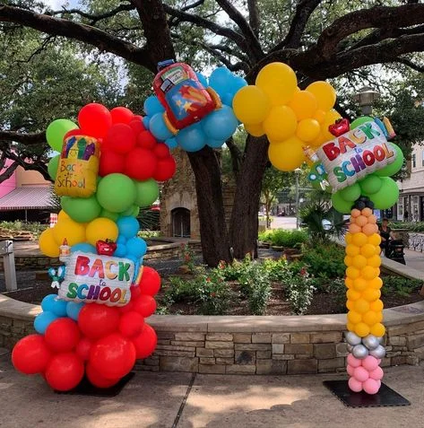Garland made of yellow, red, blue, and silver latex balloons, featuring customized "Back to School" themed bag balloons.