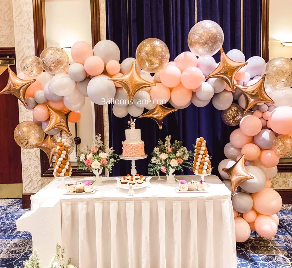 Bridal showers candy table arch balloons in shades of peach, grey and gold, adorned with confetti and star balloons in Manhattan