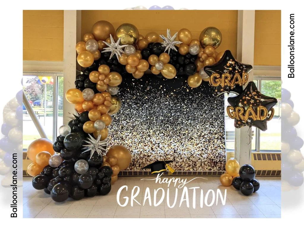 Say 'Happy Graduation!' with a stylish backdrop featuring black, gold, and silver balloons, complemented by a star-shaped silver Mylar balloon.