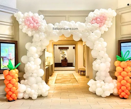 A white bunny-themed balloon arch in Brooklyn with orange and green balloon columns.