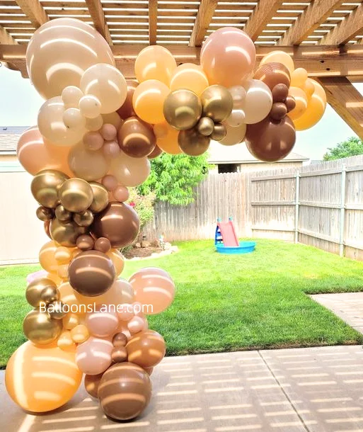 Balloon garland featuring blush pink, mocha brown, chocolate brown, ivory silk, and pearl ivory balloons, ideal for outdoor events in NYC. Suitable for various celebrations.