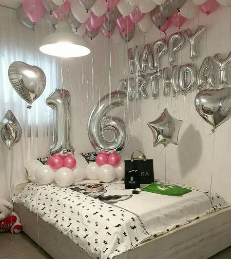 A display featuring "HAPPY BIRTHDAY" letter balloons, a number balloon, and a heart-shaped foil balloon in silver, along with pink and silver ceiling balloons in NJ