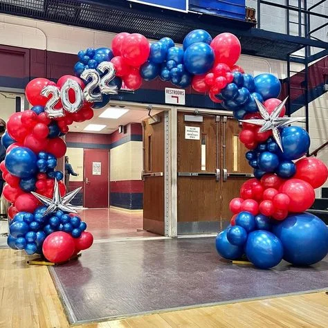 Red and blue latex balloons of various sizes, along with silver star-shaped Mylar balloons and number balloons, arranged in a garland.