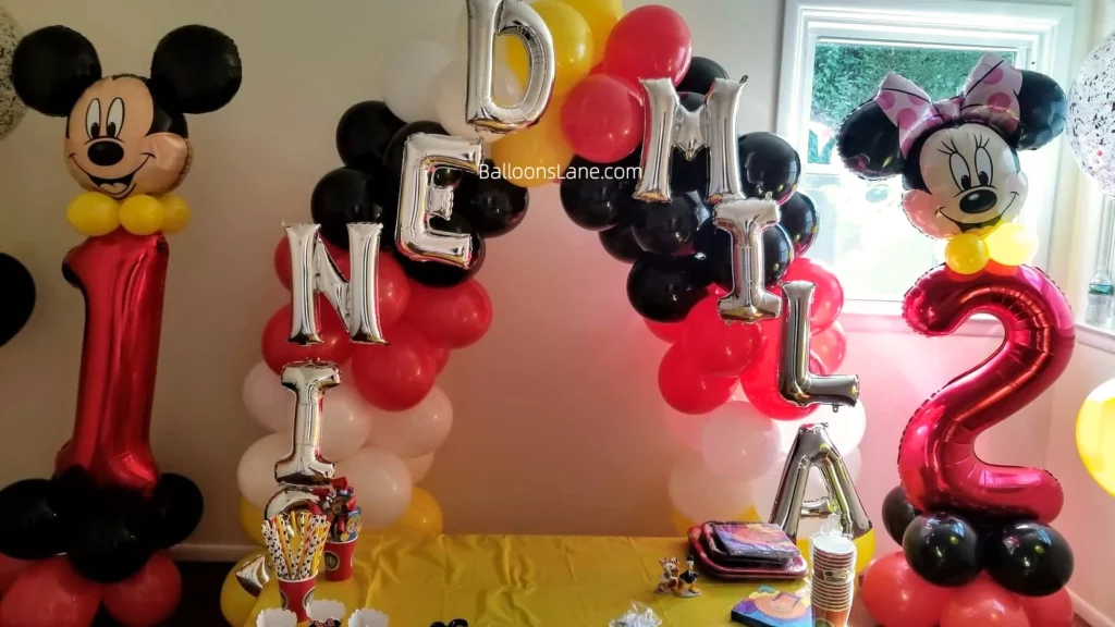 Backdrop arrangement of Minnie and Mickey Mouse number balloons with letter balloons in NYC.