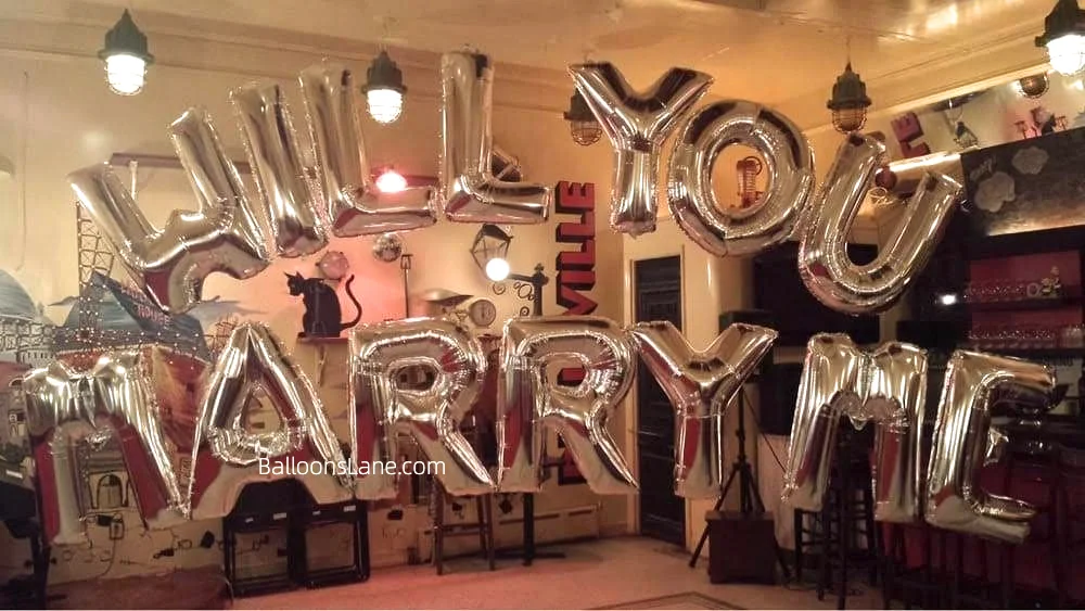 A romantic proposal setup featuring "Will You Marry Me?" letter balloons in Brooklyn.